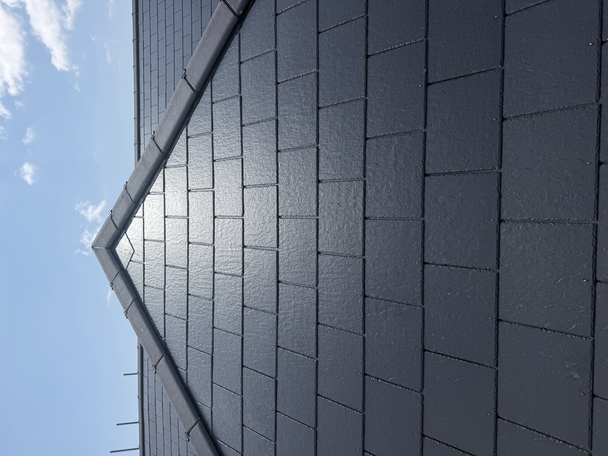 Completed dark slate pitched roof with ridge tiles at the apex