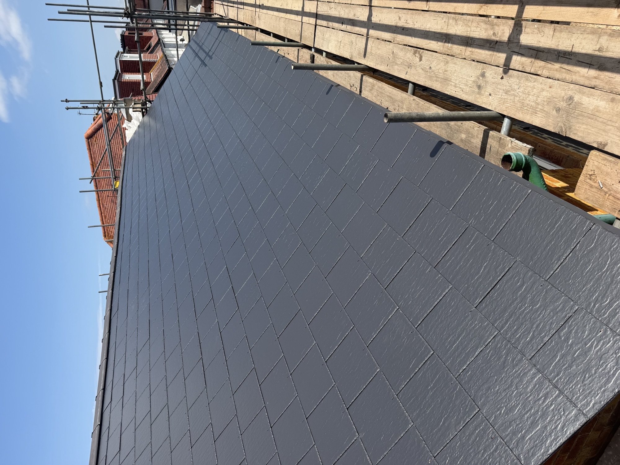 Newly covered dark slate roof slope viewed from scaffolding